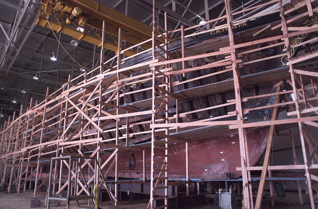 The wooden hull of a large vessel covered with scaffolding