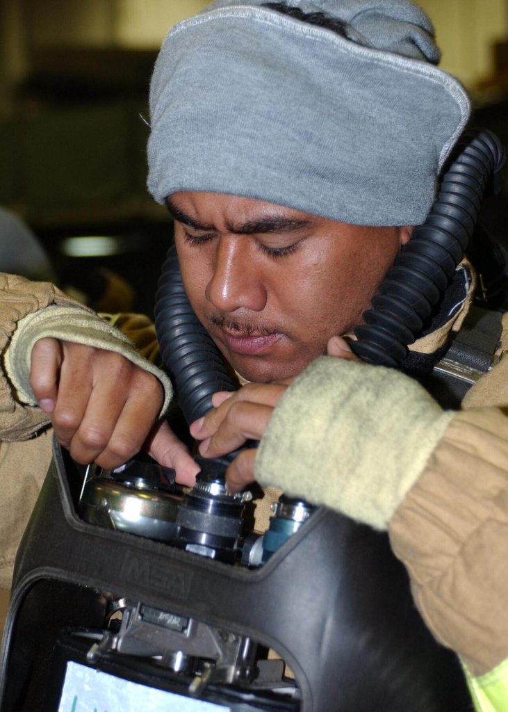 Aviation Ordnanceman 2nd Class Fong Sii, of Honolulu, Hawaii, dons his Oxygen Breathing Apparatus...