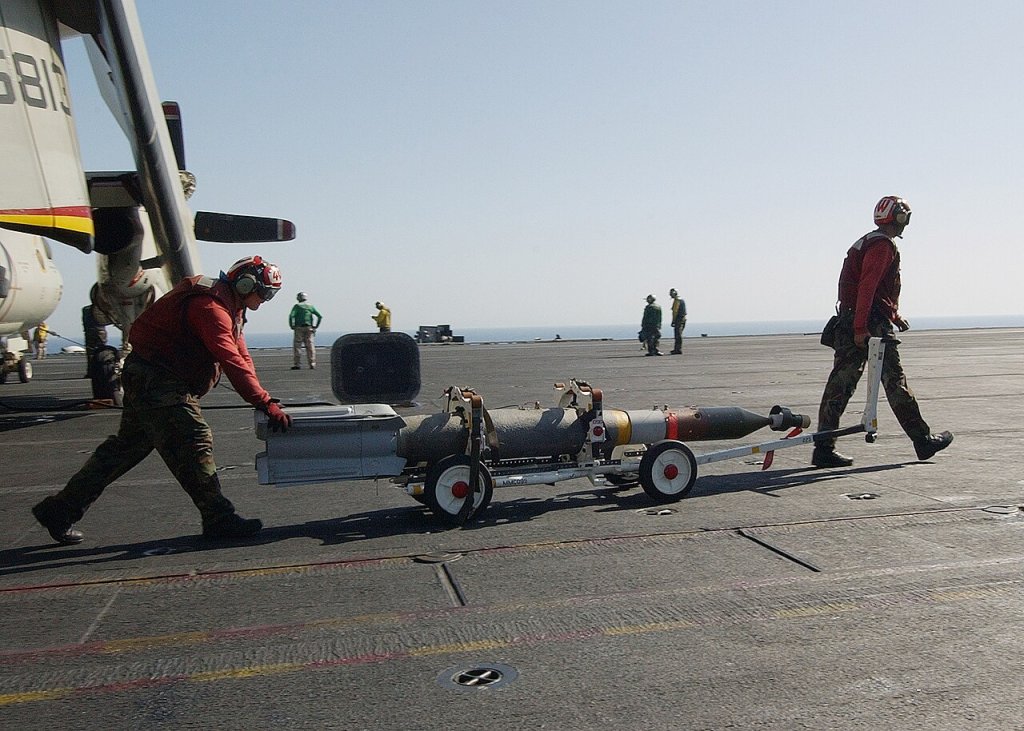 Aviation Ordnancemen transfer Guided Bomb Unit Twelve (GBU-12) bombs to an F/A-18 Hornet for ordn...
