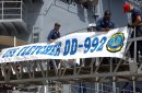 Sailors assigned to the Spruance Class destroyer USS Fletcher (DD 992) attach the ship's banner t...