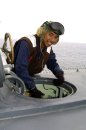 Aviation Machinist Mate 3rd Class John Barnachia opens the scuttle to the ship's Landing Signals ...